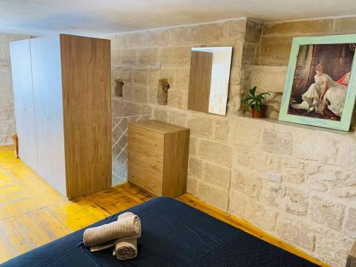 QormiにあるSerenityの石壁の客室で、ベッド1台、ドレッサーが備わります。