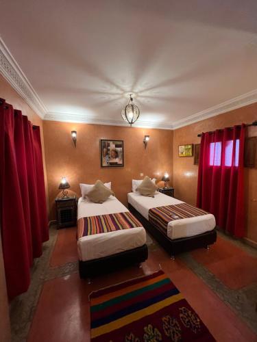 2 Betten in einem Zimmer mit roten Vorhängen in der Unterkunft Riad Andalla in Marrakesch