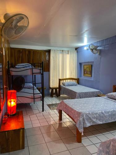 1 dormitorio con 2 camas y ventilador en Mauras Tropical Mini Hostel & Tours, en Paquera