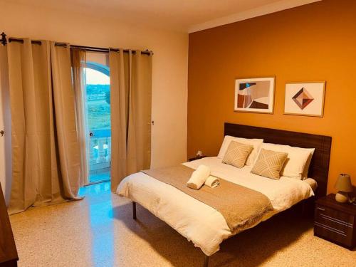 a bedroom with a large bed and a large window at Lovely 3 bedroom in Siggiewi in Siġġiewi