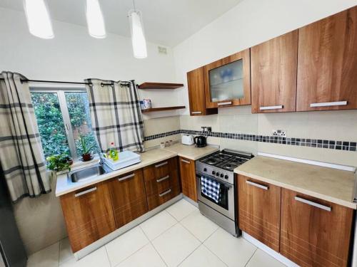 a kitchen with wooden cabinets and a stove top oven at Lovely 3 bedroom in Siggiewi in Siġġiewi