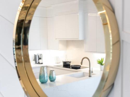 a kitchen with white cabinets and a sink in a mirror at Pristine Modern 2BR Condo Private BBQ and Balcony in Toronto
