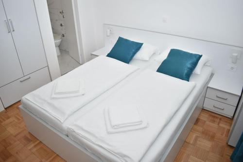 Villa Rosa Rooms في بونات: سرير أبيض مع وسائد زرقاء في الغرفة