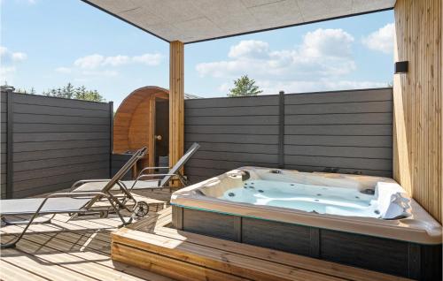a hot tub sitting on a deck with chairs at Stunning Home In Blokhus With Kitchen in Blokhus
