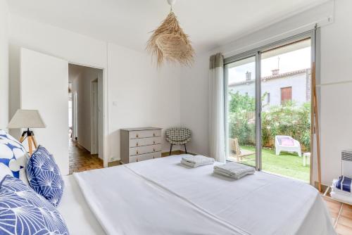 a white bedroom with a bed and a large window at Villa Cavi Laurier in Le Grau-dʼAgde
