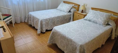 a bedroom with two beds and a night stand with a lamp at Camiño Loureiro in Combarro