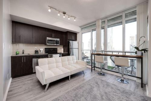 a living room with a white couch and a kitchen at Cityscape 1BR Condo with Private Balcony amd WFH setup in Toronto