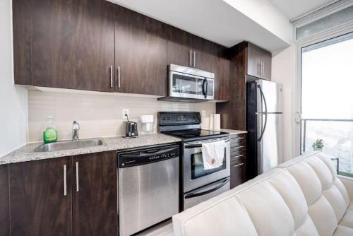 a kitchen with a stainless steel stove and refrigerator at Cityscape 1BR Condo with Private Balcony amd WFH setup in Toronto