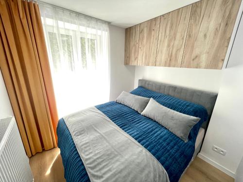 a bedroom with a bed with blue sheets and a window at Mand apartmán in Žilina