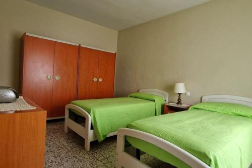 two beds in a room with green sheets and wooden cabinets at Casa Lichio in Stia