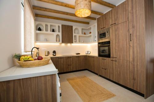 una cocina con armarios de madera y una cesta de fruta en una barra en Muses of art Villas en Afántou
