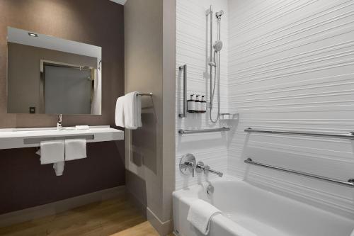 a bathroom with a bath tub and a sink at AC Hotel by Marriott Bloomington Mall of America in Bloomington