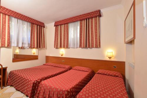 una camera d'albergo con due letti e due finestre di Hotel Chicago a Roma