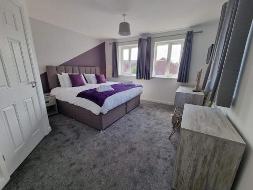 a bedroom with a large bed with purple pillows at Bristol House By Cliftonvalley Apartments in Bristol