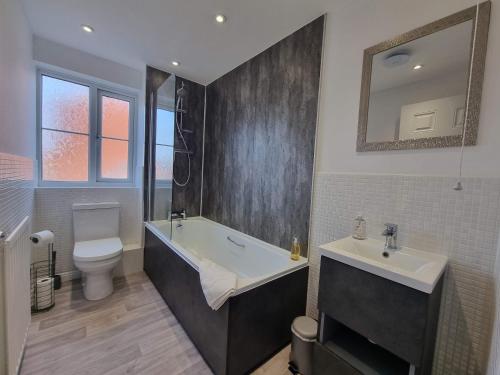 a bathroom with a tub and a sink and a toilet at Bristol House By Cliftonvalley Apartments in Bristol