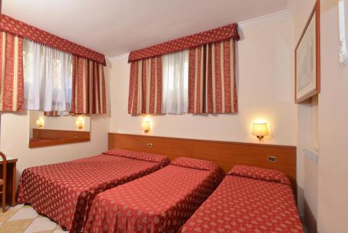 a hotel room with two beds and two windows at Hotel Chicago in Rome