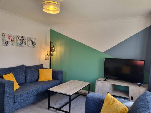 a living room with a blue couch and a tv at Bristol House By Cliftonvalley Apartments in Bristol