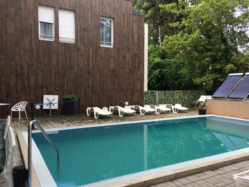 a swimming pool with a bunch of chairs next to a building at Lido Riviéra 011 Apartman in Balatonlelle
