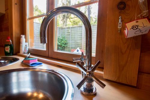 eine Küchenspüle mit einem Wasserhahn neben einem Fenster in der Unterkunft tranquil log cabin in Shepton Mallet