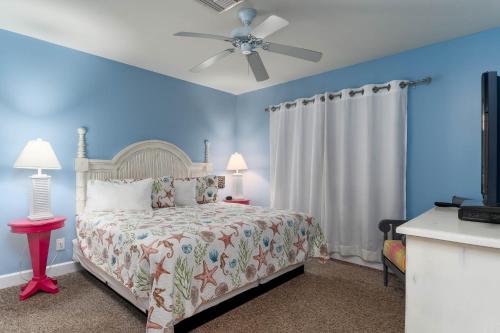 a bedroom with a bed with blue walls and a ceiling fan at Harbour House at the Inn 207 in Fort Myers Beach