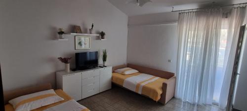 a bedroom with two beds and a television in it at Apartments Vuko Seget Vranjica in Seget Vranjica