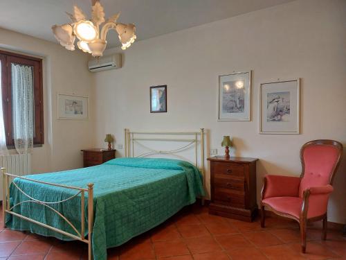 sypialnia z łóżkiem, krzesłem i żyrandolem w obiekcie Casa Vacanze - La Ginestra w mieście Ginestra