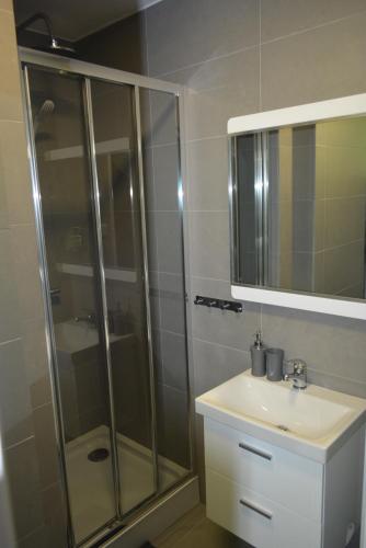 a bathroom with a shower and a sink and a mirror at Sizen Rewal - Pokoje Gościnne Noclegi Apartament z osobnym wejściem Taras Wi-Fi in Rewal