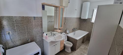 a bathroom with a sink and a toilet and a mirror at Apartments Vuko Seget Vranjica in Seget Vranjica
