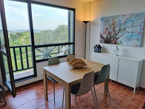 uma sala de jantar com mesa e cadeiras e janelas grandes em Bonito dúplex con vistas al mar em Comillas