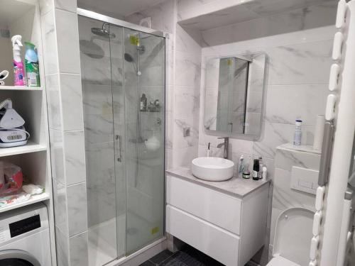 uma casa de banho branca com um chuveiro e um lavatório. em Appartement cosy Puteaux centre em Puteaux