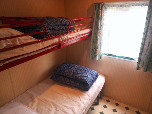 Cette petite chambre comprend des lits superposés et une fenêtre. dans l'établissement Mobil-home + jardin au Camping du lac, à Égletons