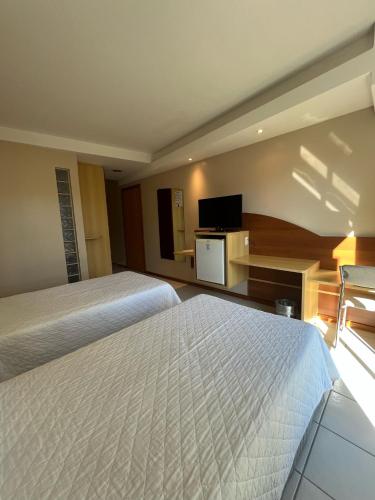 a hotel room with two beds and a flat screen tv at Hotel Aliança Express in Rio do Sul