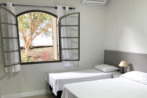 two beds in a room with a window at Hotel Turi in Barra Bonita