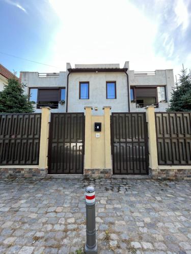 ein Haus mit einem schwarzen Zaun und einem Tor in der Unterkunft Vila AlMare in Eforie Nord