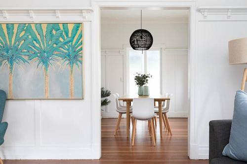 a dining room with a table and a palm tree painting at Pet Friendly Family Home 3km to CBD in Brisbane