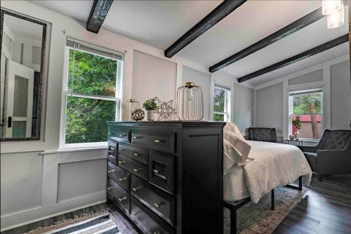 a bedroom with a black dresser and two windows at Cozy Cottage at the Springs in De Leon Springs