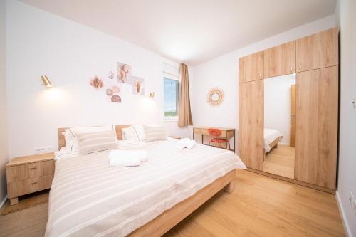een slaapkamer met een groot bed met witte lakens bij Vrsi Seaside Heights Apartments in Vrsi