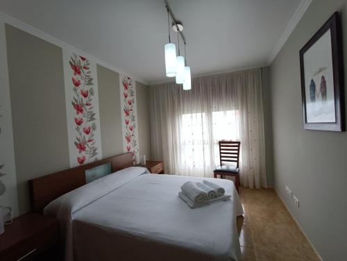 Apartamento Isla de Arousa - Riasón في إيسلا دي أروسا: غرفة نوم بسرير وكرسي ونافذة