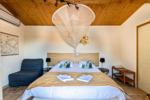 une chambre avec un grand lit et une chaise bleue dans l'établissement La Rose des Vents Chambres d'hôtes & Spa, à Néoules