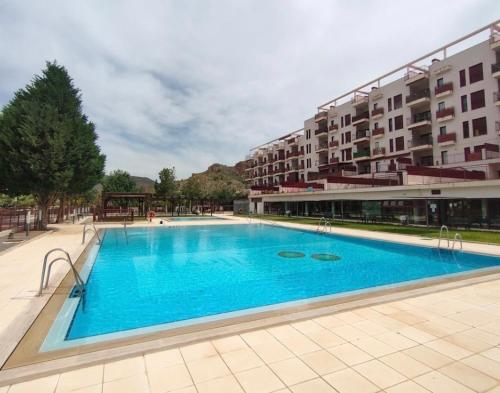 uma grande piscina azul em frente a um edifício em Apartamento Natur Spa em Villanueva de Río Segura