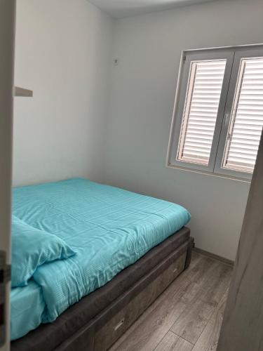 a bed in a room with two windows at Apartment Kovac in Herceg-Novi