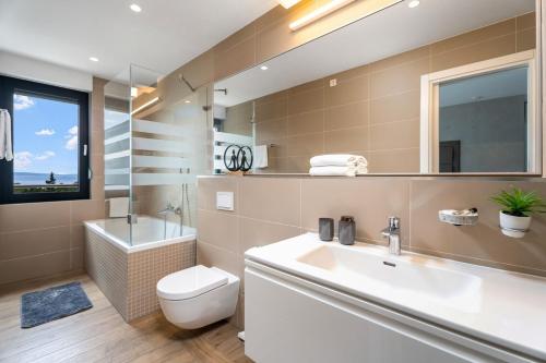 a bathroom with a sink and a toilet and a mirror at Luxury, seafront Villa IVAN with heated pool only 100m from beach in Omiš