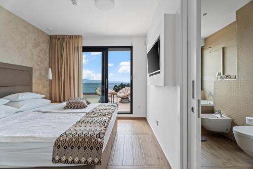 a bedroom with a bed and a tub and a sink at Luxury, seafront Villa IVAN with heated pool only 100m from beach in Omiš