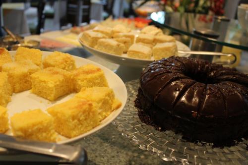 a table with two plates of cakes and a chocolate cake at Hotel Aliança Express in Rio do Sul