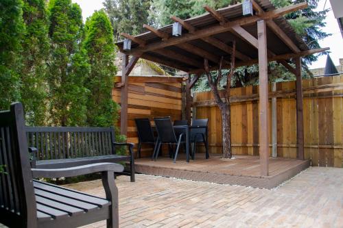 a wooden gazebo with chairs and tables on a patio at Season One Apartman in Szeged