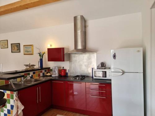a kitchen with red cabinets and a white refrigerator at Gîte avec Piscine au cœur de la Vallée de la Cèze in Saint-Laurent-de-Carnols