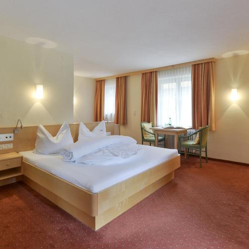 a hotel room with a large bed and a table at Alpine Lifestyle Berghotel Madlener in Damuls