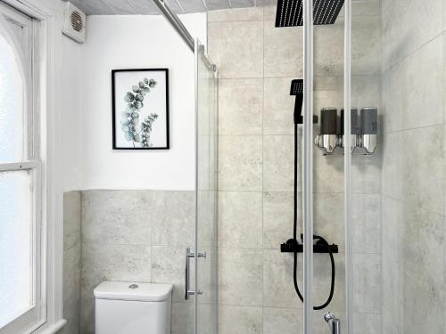 um chuveiro com uma porta de vidro na casa de banho em Erin Court Mansions - Suite 10 em Croydon