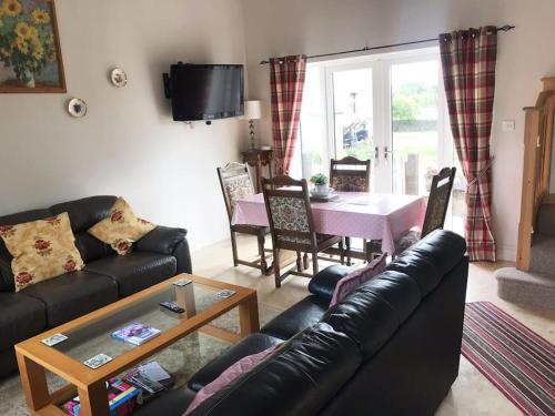 a living room with a black leather couch and a table at Kenns Farm - 2 Beautiful Barns in Carterton