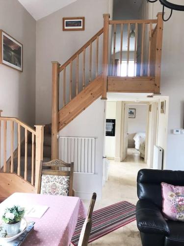 a living room with a table and a staircase at Kenns Farm - 2 Beautiful Barns in Carterton